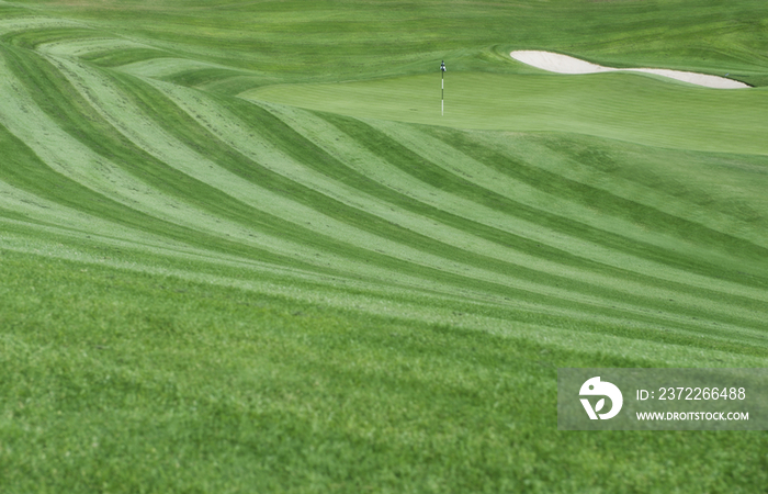 A golf course with mown fairways creating a pattern on an undulating landscape
