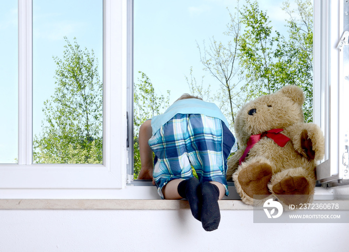 Junge beugt sich aus dem Fenster