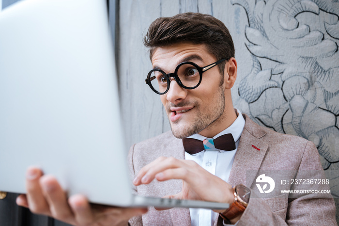 Nerd man holding laptop and making funny face