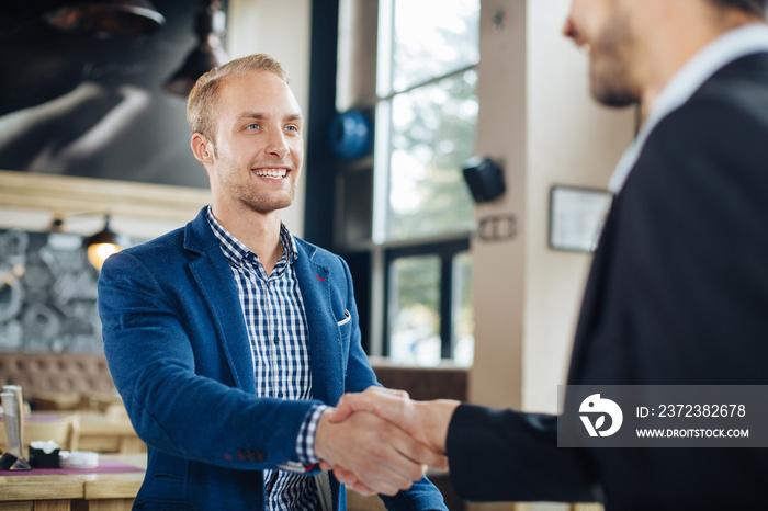 Two businessman shaking hands in a cafe