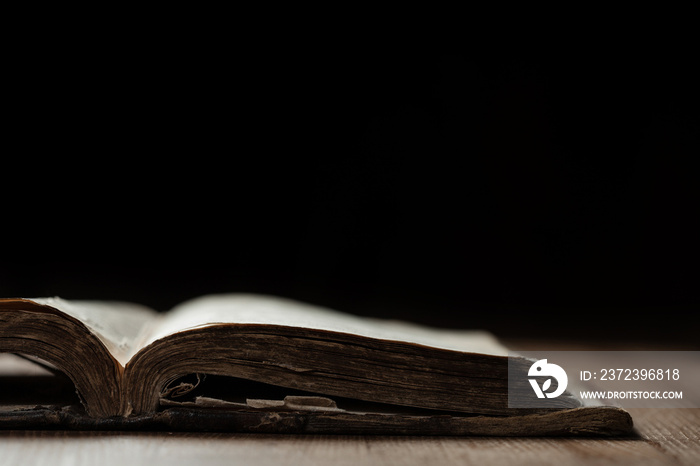 Image of an old Holy Bible on wooden background in a dark space with shallow depth of field