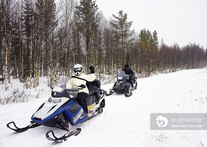 Woman and a Man driving snow mobile in Ruka of Lapland