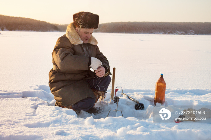 Man ice fishing in frozen lake