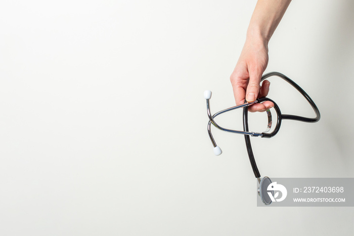 female hand holds a stethoscope on a white background