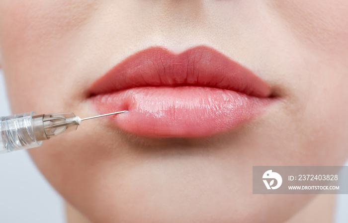 Beautiful young woman receiving filler injection in lips, closeup