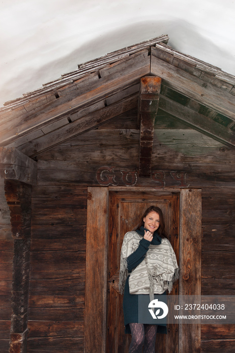 Portrait smiling woman standing in wood cabin doorway