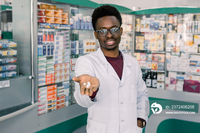 African-american doctor pharmacist man holding and offering white pills. Drug store and drug quality