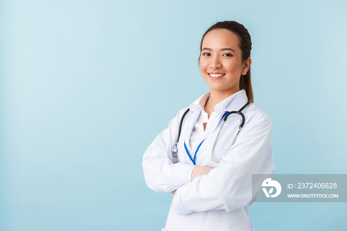 Woman doctor posing isolated over blue wall background with stethoscope.