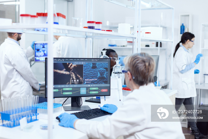 制药实验室的高级科学家穿着实验室外套与团队一起进行基因研究