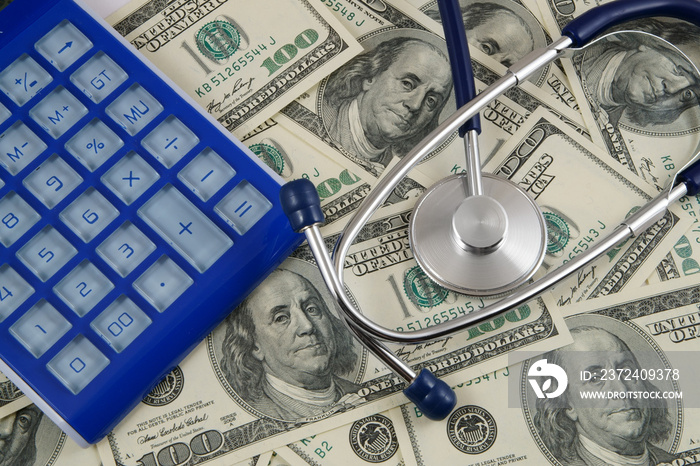 Blue calculator and stethoscope on money background, cost of healthcare concept