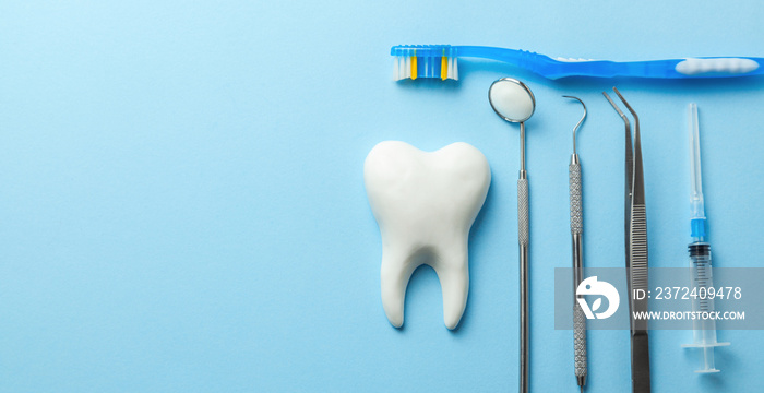 Tooth and dental instruments on blue background. Dental treatment. Dentist tools mirror, hook, tweez