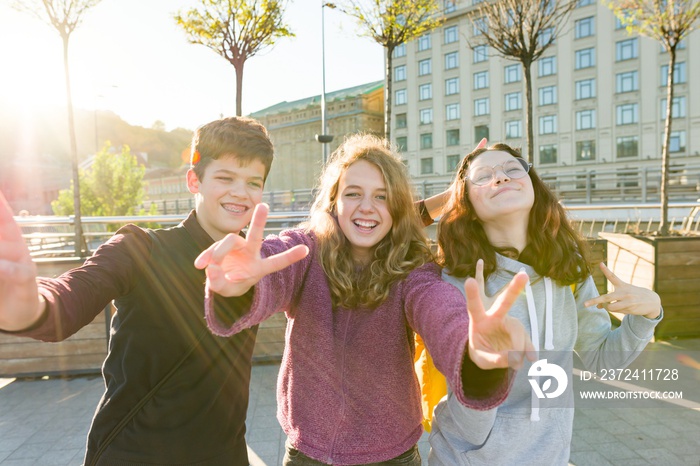 Portrait of friends teen boy and two girls smiling, making funny faces, showing victory sign in the 