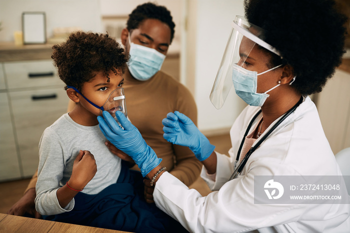 Small black boy receiving asthma treatment while doctor is vising him at home due to COVID-19 pandem