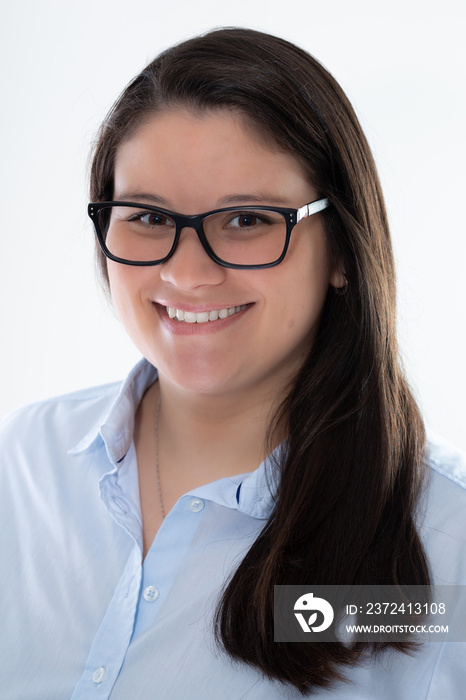 Young professional lady poses for a studio headshot. She is caucasian with long hair. She is smiling