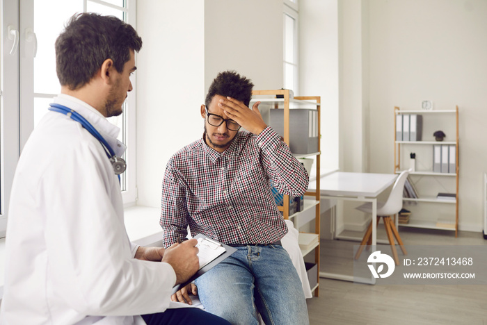 男性医生咨询患病的少数民族患者，他们感到不健康的头痛。不健康的人会受苦