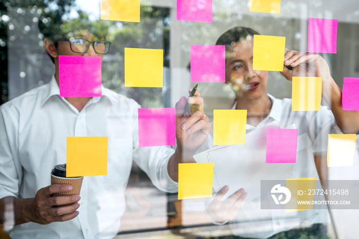 Young creative team using post it notes in glass wall to writing strategy plan