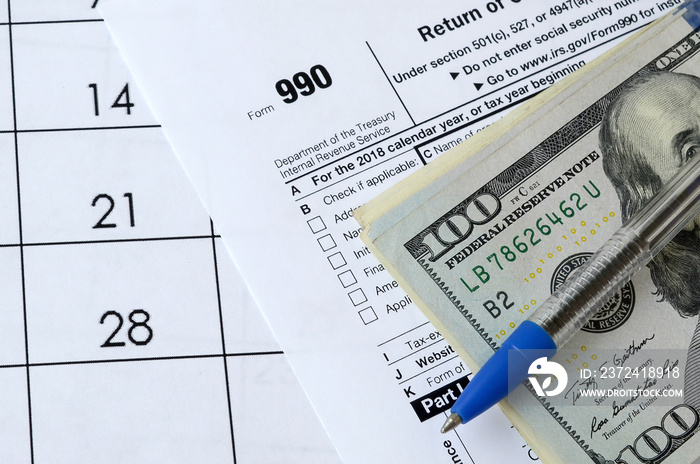 990表格免缴所得税的组织申报表和带美元钞票的蓝笔放在办公室里