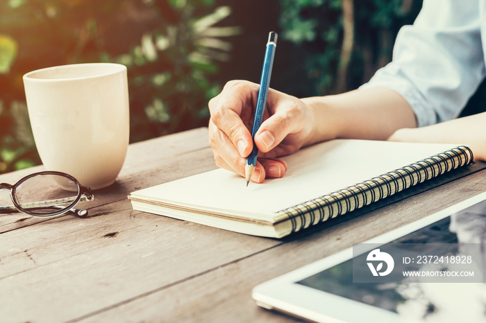 Female hand with pencil writing on notebook.