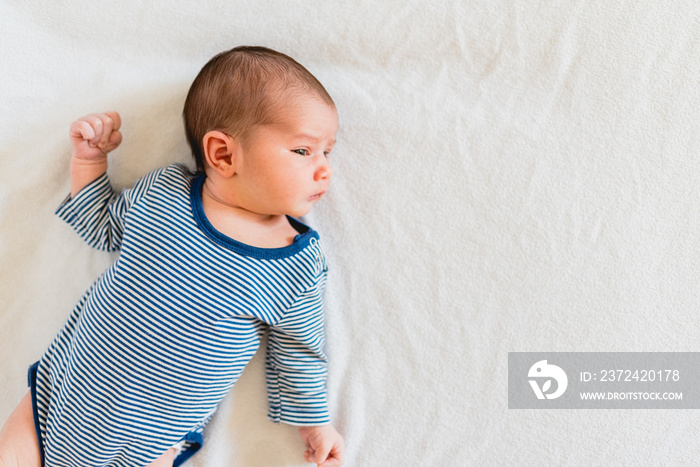 Portrait of pretty newborn girl lying on her bed and looking at the camera.