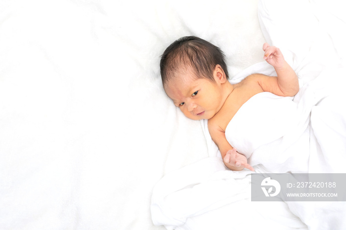 Cute newborn baby girl in white blanket on nursery bed. Adorable new born child, little boy eyes loo