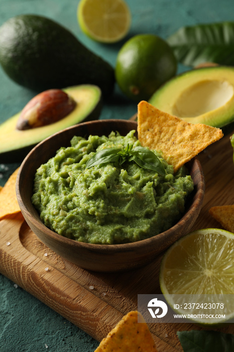 Concept of tasty eating with bowl of guacamole on green textured background