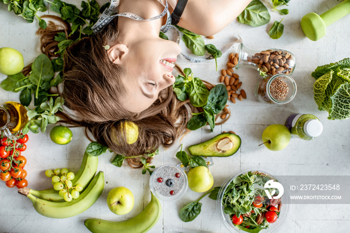 Beauty portrait of a woman surrounded by various healthy food lying on the floor. Healthy eating and