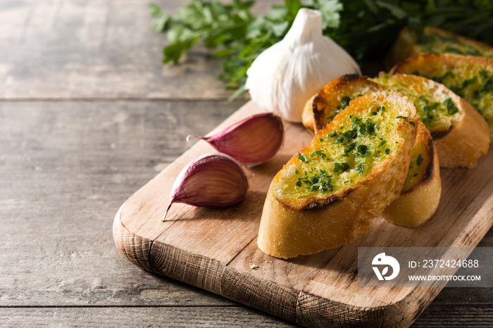 Garlic breads slice and ingredients on wooden table. Copyspace