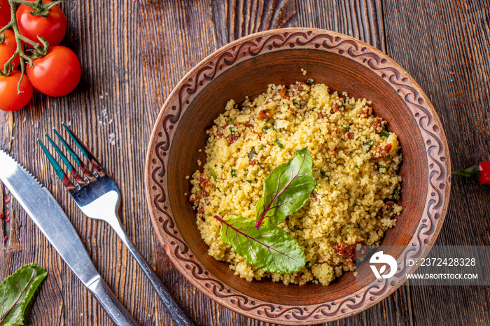 Couscous in bowl with olive oil and dried tomatoes on wooden background, oriental cuisine, horizonta