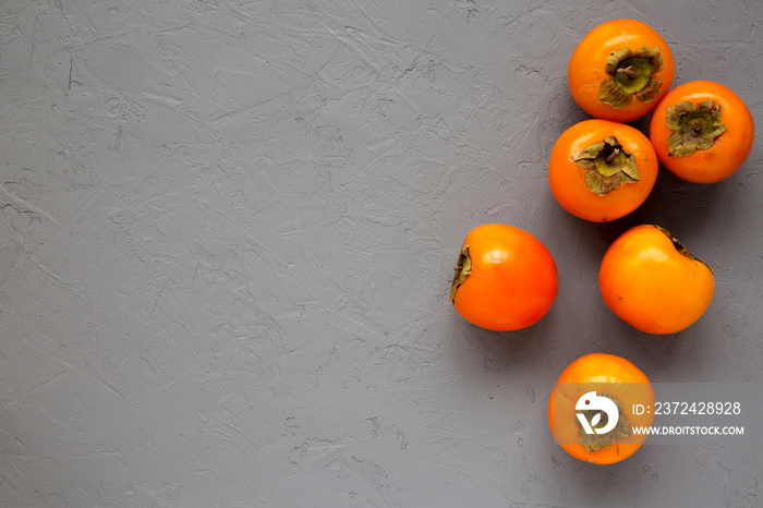 Raw Ripe Orange Persimmons on gray surface, top view. Flat lay, overhead, from above. Space for text