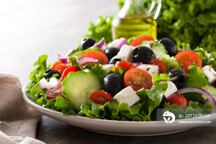 Fresh Greek salad in bowl with black olive,tomato,feta cheese, cucumber and onion on wooden table.