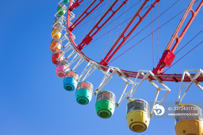 Amazing colorful ferris wheel in amusement park with sunshine blue sky in the morning with copy spac