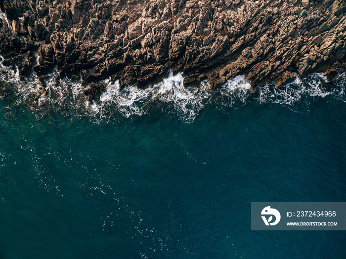 Top view Azure blue sea with waves beating on beach and rocks. Aerial photo