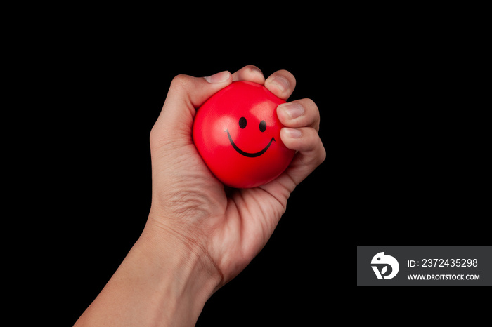 Hand squeezing a red stress ball isolated on black background with clipping path.