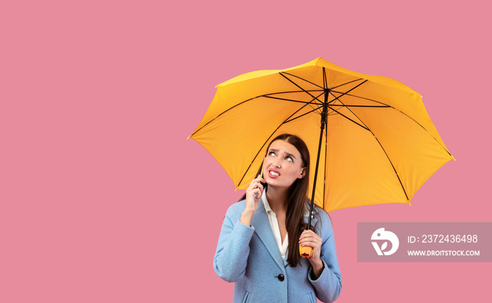 Portrait of angry young girl holding yellow umbrella