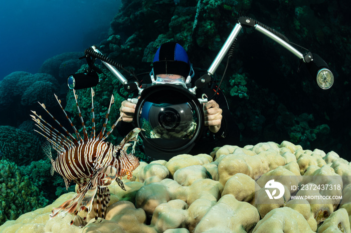 red lionfish fish on reef with an underwater photographer diver