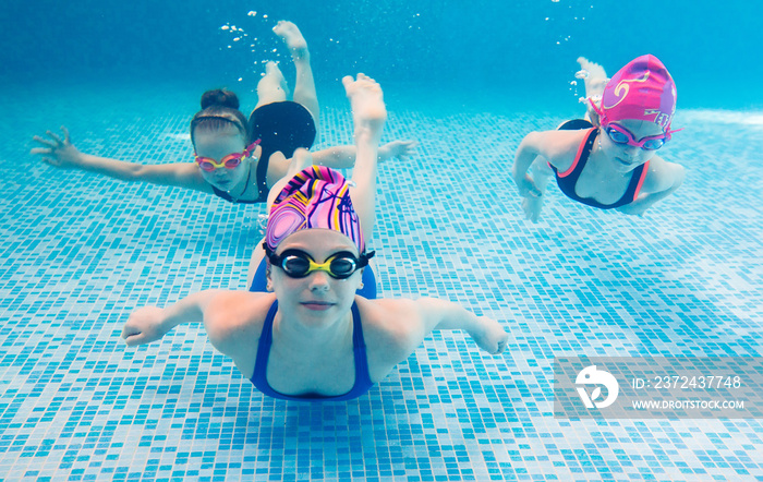 Underwater photo of young friends in swimming pool.