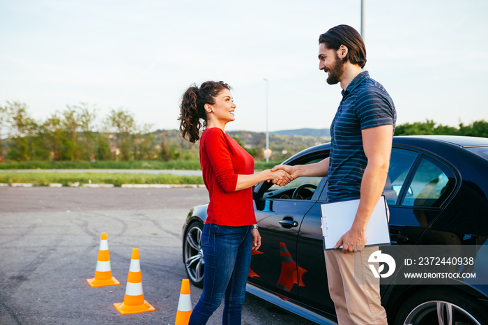 Driving school or test. Beautiful young woman with instructor learning how to drive and park car bet