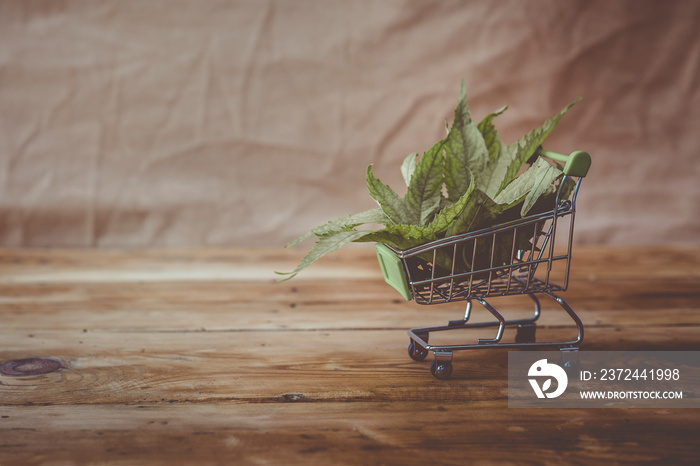 Cannabis leaves in the shopping cart. Drug shopping, marihuana legalization, drug business concept