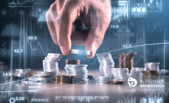 Male hand stacking coins. Investment graphs and charts