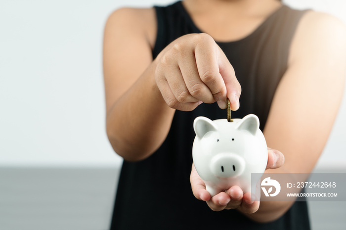 Money saving and donation concept, child put money on cute white piggy bank