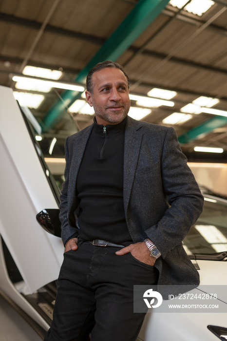 Mature man leaning against luxury car