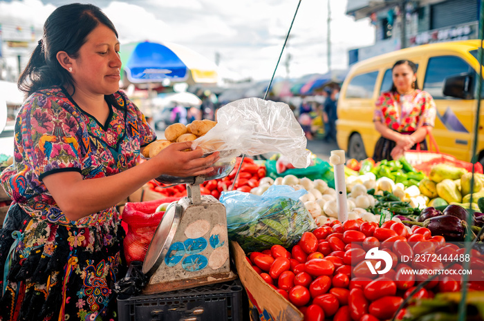 Mujer indígena vendiendo vegetales en un mercado guatemalteco.