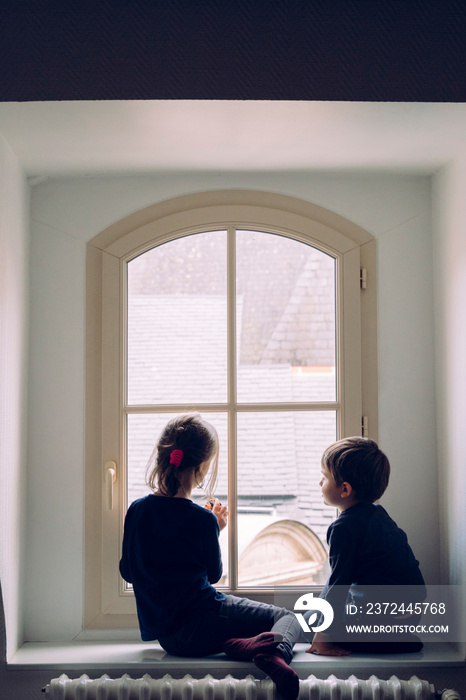 Small siblings waiting for Santa Claus looking through the window. Children hope and imagination aro