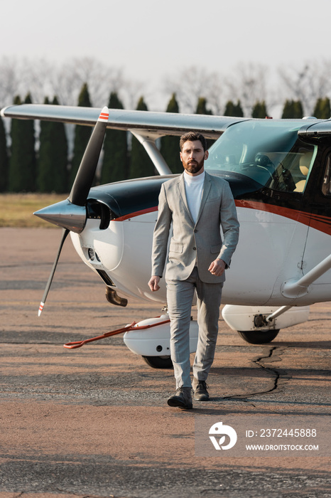full length of bearded businessman walking near helicopter outdoors.
