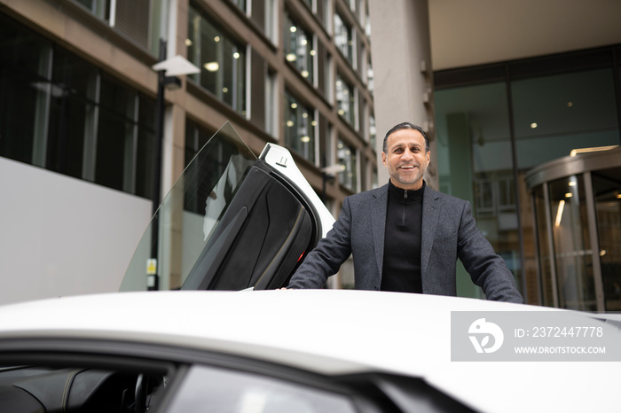 Smiling mature man leaning against luxury car