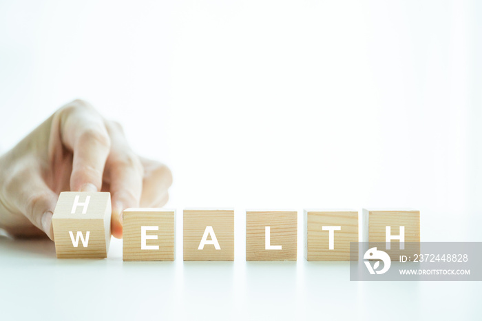 Words Health and Wealth on the wooden block close up, man turning the words between health and wealt