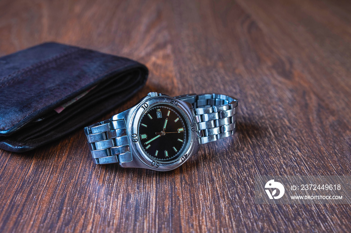 Stainless steel watch and purse on a wooden background