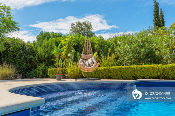 私人别墅花园中的豪华游泳池，休闲游客的带枕头的吊椅，在