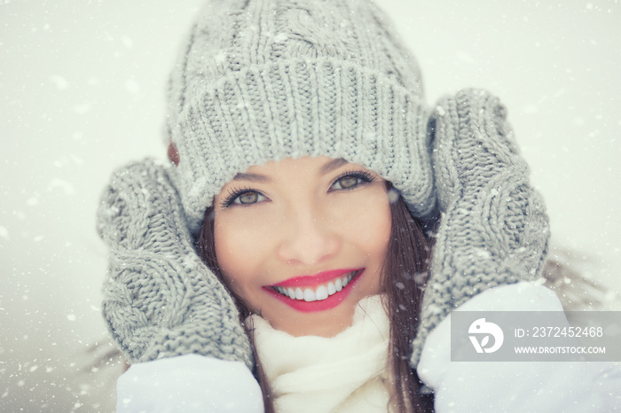Beautiful smiling young woman in warm clothing. The concept of portrait in winter snowy weather