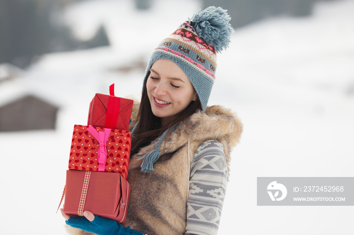 Young woman carrying Christmas gifts in snow